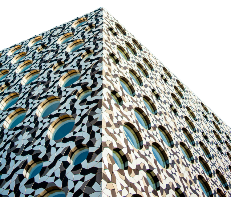 A patterned modern building with portholes in Greenwich, set against blue sky.